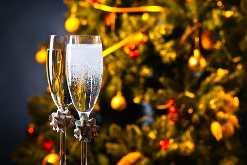 Two glasses with champagne and Christmas ornaments , focus on a foreground.