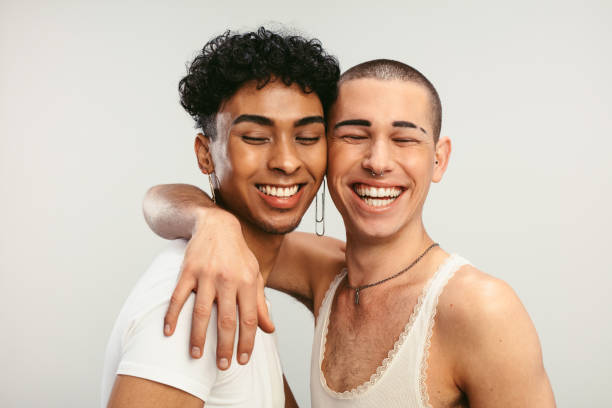 Happy young gay couple in love Young gay couple in love on a white background. Two young androgynous men smiling together. transgender couple portrait stock pictures, royalty-free photos & images