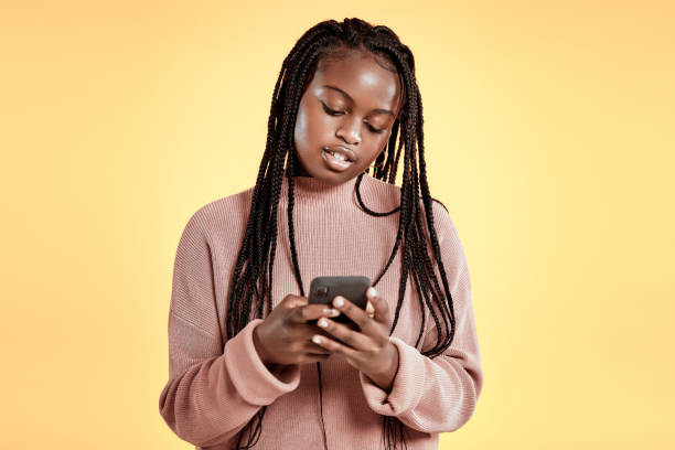 Beautiful teenager using smartphone on yellow background Cool teenage girl using smartphone on yellow background, copy space cute 15 year old girls stock pictures, royalty-free photos & images