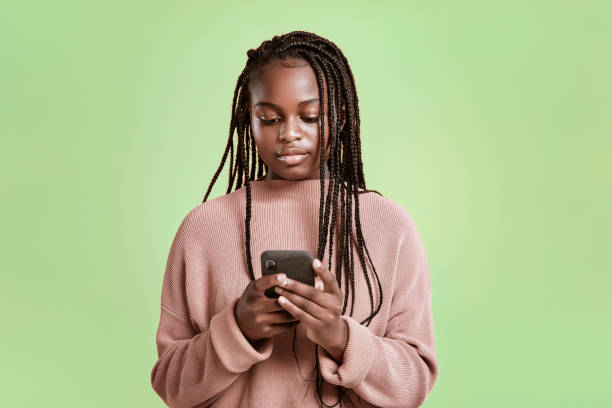 istock Beautiful teenager using smartphone on green background 1284547402