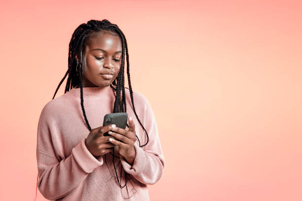 istock Beautiful teenager using smartphone on pink background 1284547410