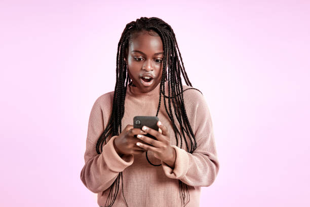 istock Beautiful teenager using smartphone on purple background 1284547411