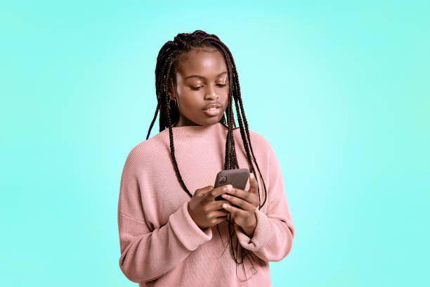 istock Beautiful teenager using smartphone on blue background 1284547416