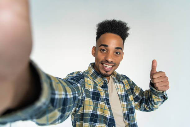 istock Young african man take selfie with thumbs up isolated on white background 1284547530