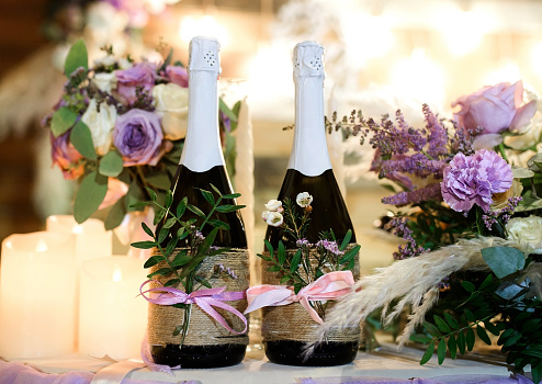 Two bottles of champagne decorated with flowers on the wedding table. Wedding decor.