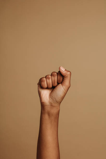 Close up of fist Fist held tightly against brown background. Close fist symbolizing the protests movement. black civil rights stock pictures, royalty-free photos & images