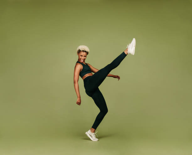 Fitness woman doing stretching exercise African american female athlete doing warm up exercises. Woman in fitness wear raising her leg doing stretching exercises. stretched leg stock pictures, royalty-free photos & images