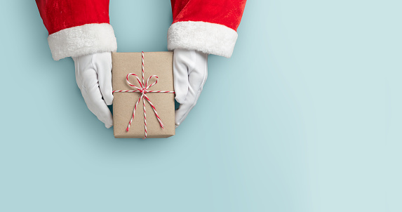 Merry Christmas concept, Top view of Santa claus hands is holding a brown gift box or present box over blue isolated background.