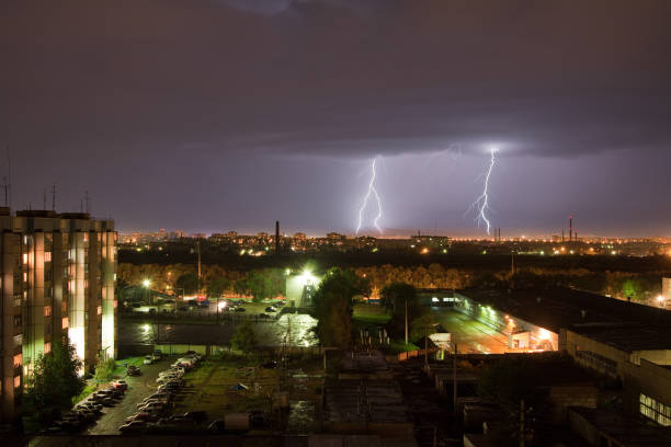 istock Powerful thunderbolt hits the city at night. A strong lightning strike over a dark gray sky hits the ground, illuminating the industrial area around. 1284550616