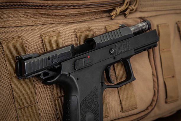 istock A modern black pistol on a brown military backpack. Weapons for defense and attack. Arming the police, army and special units. 1284550787