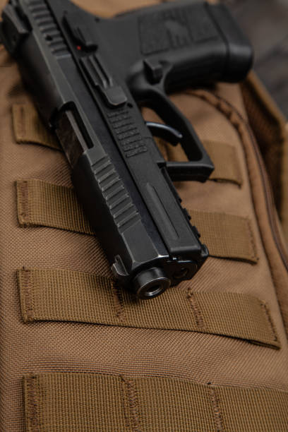 istock A modern black pistol on a brown military backpack. Weapons for defense and attack. Arming the police, army and special units. 1284550797
