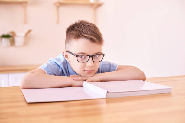 little boy in eyeglasses thinking at home. schoolboy study - eye exam child optometrist human eye imagens e fotografias de stock