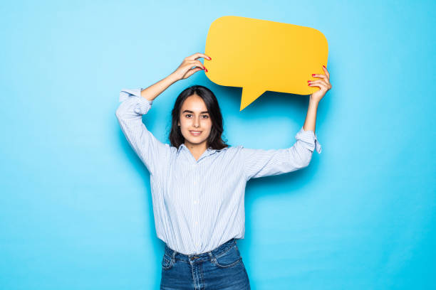 istock Young girl holding a speech bubble isolated on blue background 1284555527