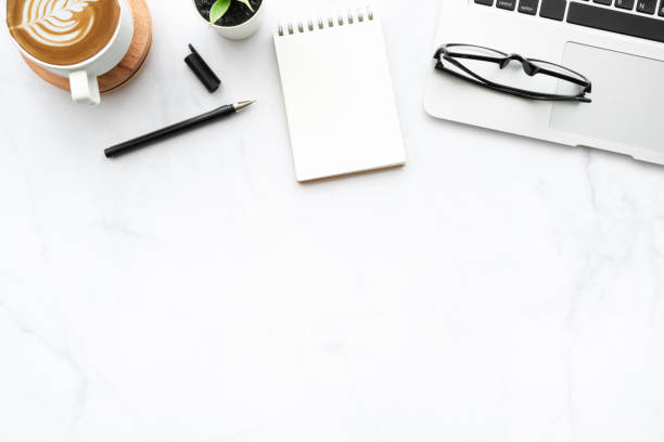 istock White marble office desk table with small blank notebook page, laptop computer, cup of latte coffee and supplies. Top view with copy space, flat lay. 1284555546