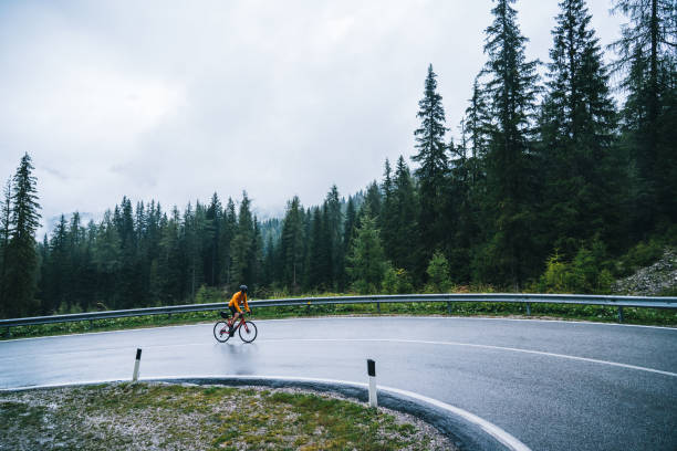 radfahrer fährt im regen auf nasser fahrbahn - racing bicycle cycling professional sport bicycle stock-fotos und bilder