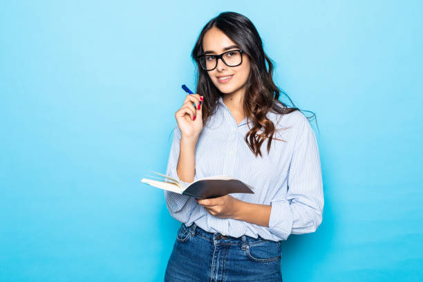 istock Young girl bought new planner, writing down notes or lecture, smiling joyfully, holding red notebook, decide start secret diary, standing over blue background 1284556557