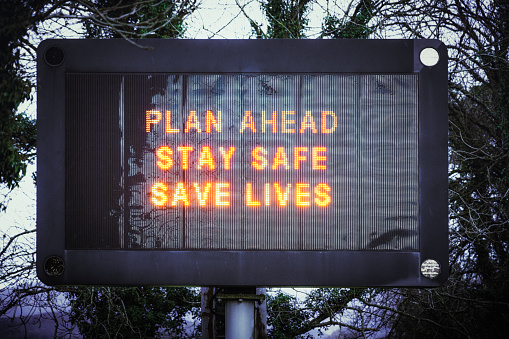 A large illuminated road sign giving advice to the public during the Covid-19 pandemic - 'Plan Ahead, Stay Safe, Save lives'.