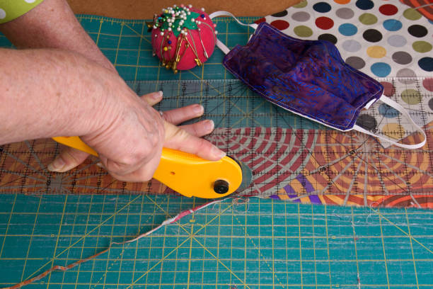 istock Woman's hands using a rotary cutter to cut leftover quilting fabric for hand sewn face masks 1284561331
