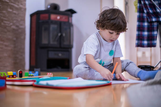 istock Beautiful toddler boy drawing using paper and crayons. 1284564560