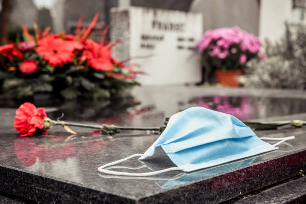 Victim of COVID-19 Surgical mask on tombstone. RIP victim of Coronavirus. death stock pictures, royalty-free photos & images