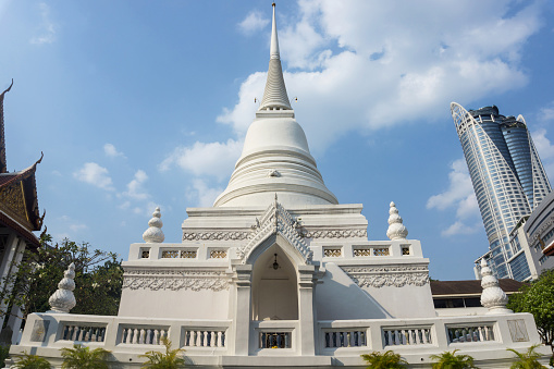 Huge statue of sitting man in front of stupas of temple Wat Phichaiyat in Bangkok. Temple is built in 1841 and dedicated to King Rama III whois sitting on throne.