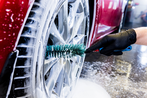 Cleaning the car wheel with a brush and water.