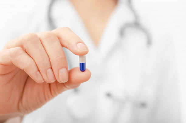 istock Female model in white scrub holds pill in her hand closeup view 1284569262