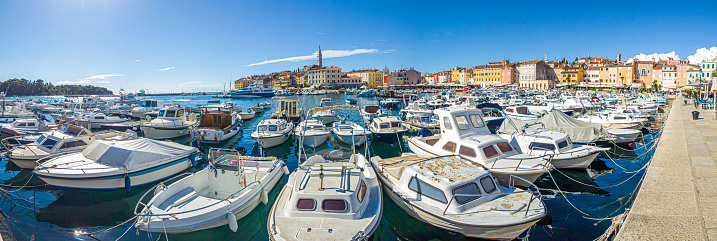 Panoramic picture over Rovinj harbor with lots of boats in front of the city at evening time