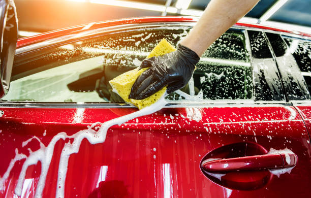 istock Worker washing red car with sponge on a car wash 1284570199