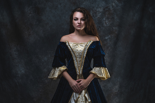 Beautiful woman in renaissance dress on abstract dark background, studio shot