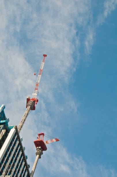 Underconstruction building in progress with many construction cr Underconstruction building in progress with many construction cranes and bright sunny blue sky with cloud construction skyscraper machine industry stock pictures, royalty-free photos & images