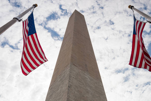 Washington Monument with flags under clouds stock photo