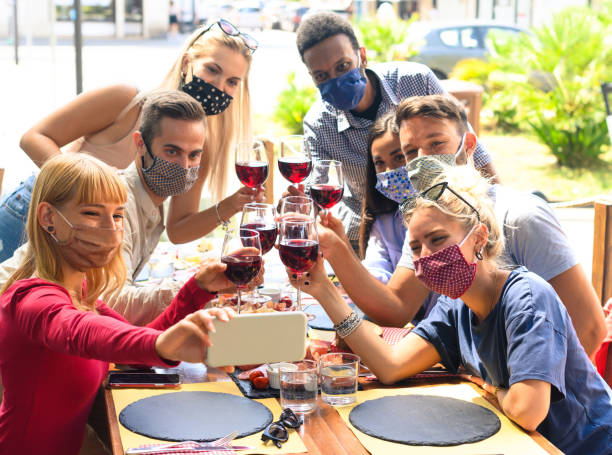 istock Friends with face mask taking selfie while toasting red wine at restaurant - Young people having fun with drinks -  The new normal lifestyle concept 1284576868