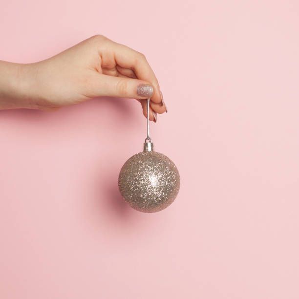 Christmas balls decoration in female hand on pink background Christmas balls decoration in female hand on pink background christmas nails stock pictures, royalty-free photos & images