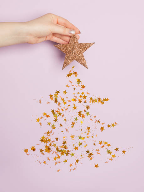 istock Christmas card composition with Xmas tree made from falling golden confetty stars on pastel purple background 1284577240
