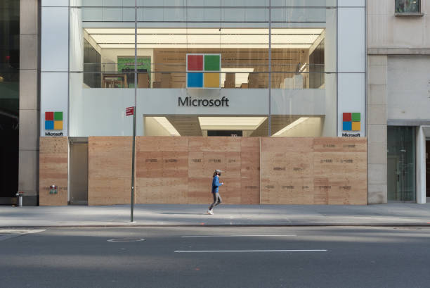New York during the COVID-19 emergency. Manhattan, New York. November 04, 2020. A woman wearing a mask jogs in front of a boarded up Microsoft store on Fifth avenue. microsoft stock pictures, royalty-free photos & images