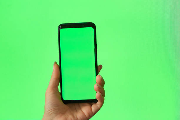 istock green screen phone woman using smartphone. Female hand touching, clicking, tapping, sliding, dragging and swiping on chroma key green screen background 1284578320