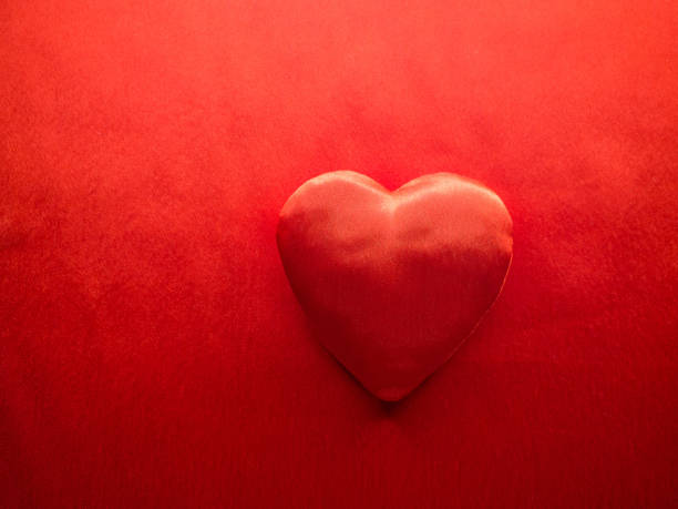 Simple classic red silk handmade heart on red background. Valentines Day, love or donor concept. Cloth texture