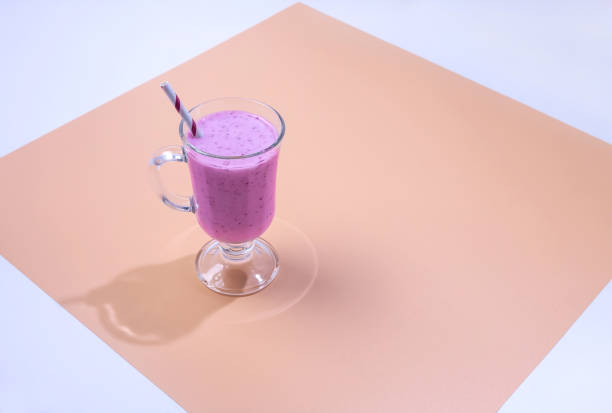 un verre de smoothie blackberry sur un fond coloré - milk shake smoothie blackberry isolated photos et images de collection