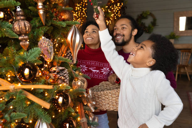 Close up happy African American parents with son decorating tree