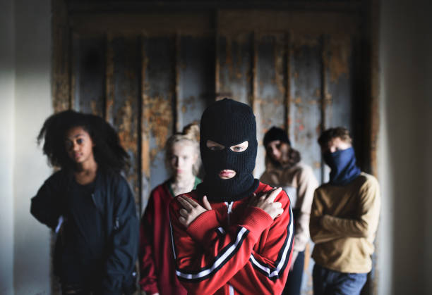 garçon avec le masque avec le gang d’adolescents à l’intérieur dans le bâtiment abandonné, montrant le geste de pistolet de doigt. - youth culture gang member adolescence family photos et images de collection