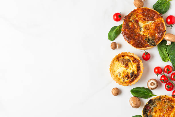 istock Chicken, mushroom, spinach and tomatoes pies quiche on white marble table. top view 1284584198