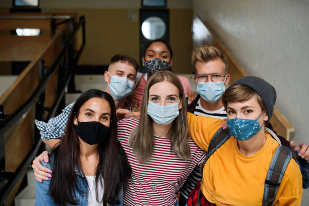 istock Front view of young students with face masks back at college or university, coronavirus concept. 1284584627