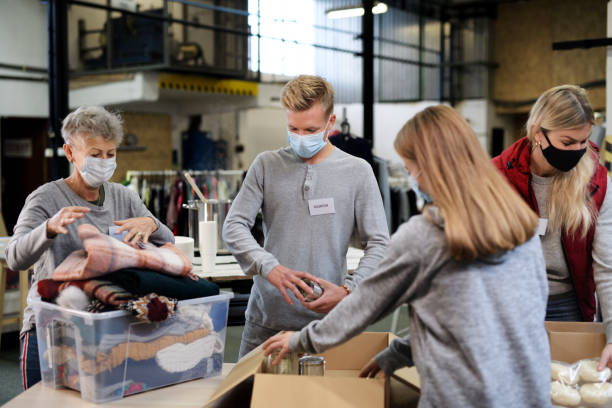 Group of volunteers in community charity donation center, food bank and coronavirus concept. Group of volunteers working in community charity donation center, food bank and coronavirus concept. altruism photos stock pictures, royalty-free photos & images