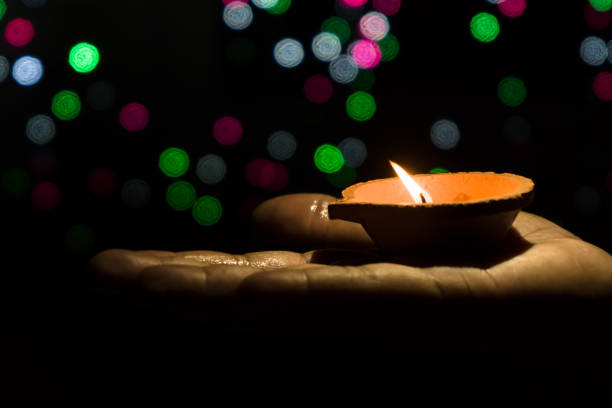 istock Diwali Diya (oil lamp) in hands with bokeh background. 1284587117