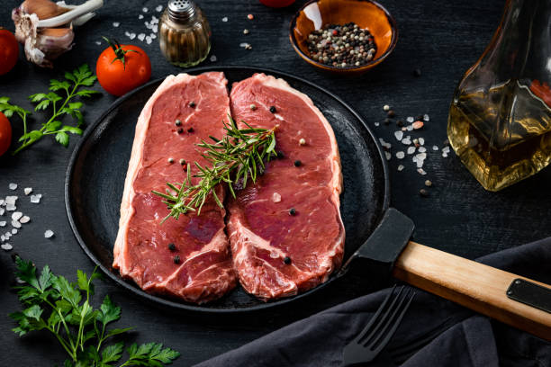 istock Raw beef steaks in a pan and spices for their preparation on a black background, close-up 1284587506