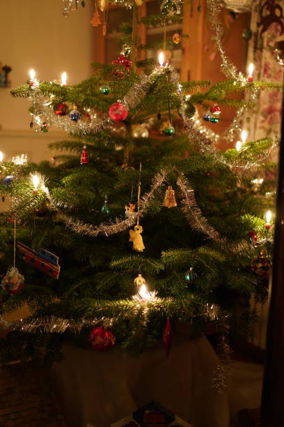 istock Christmas tree with burning candles, wreath, tinsel and colorful baubles. 1284588249