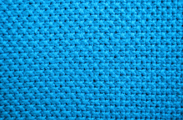 istock Texture of blue knitted sweaters. Seed stitch knit fabric background closeup, selective focus 1284588717