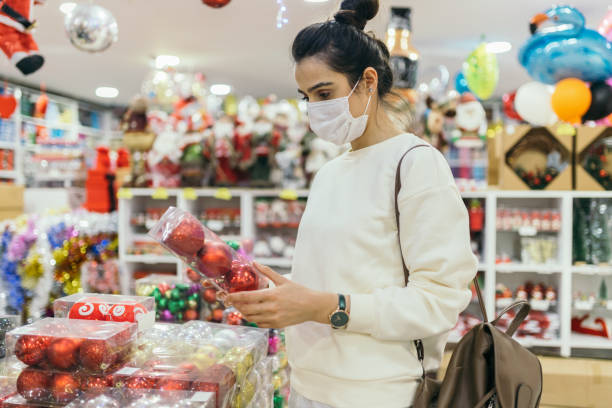 Woman wearing protective face mask and looking at a christmas market stall Woman wearing protective face mask and looking at a christmas market stall holiday shopping stock pictures, royalty-free photos & images