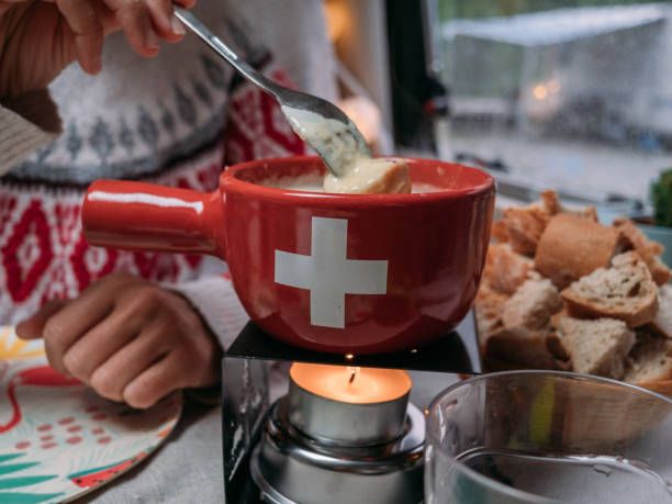 fermez-vous vers le haut sur la fondue de fromage de mangeant - fondue swiss culture winter cheese photos et images de collection